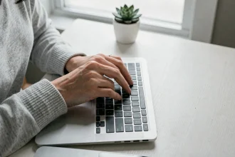 Femme appuyant sur la touche flèche gauche d'un clavier MacBook Pro, vue de dessus en plan serré