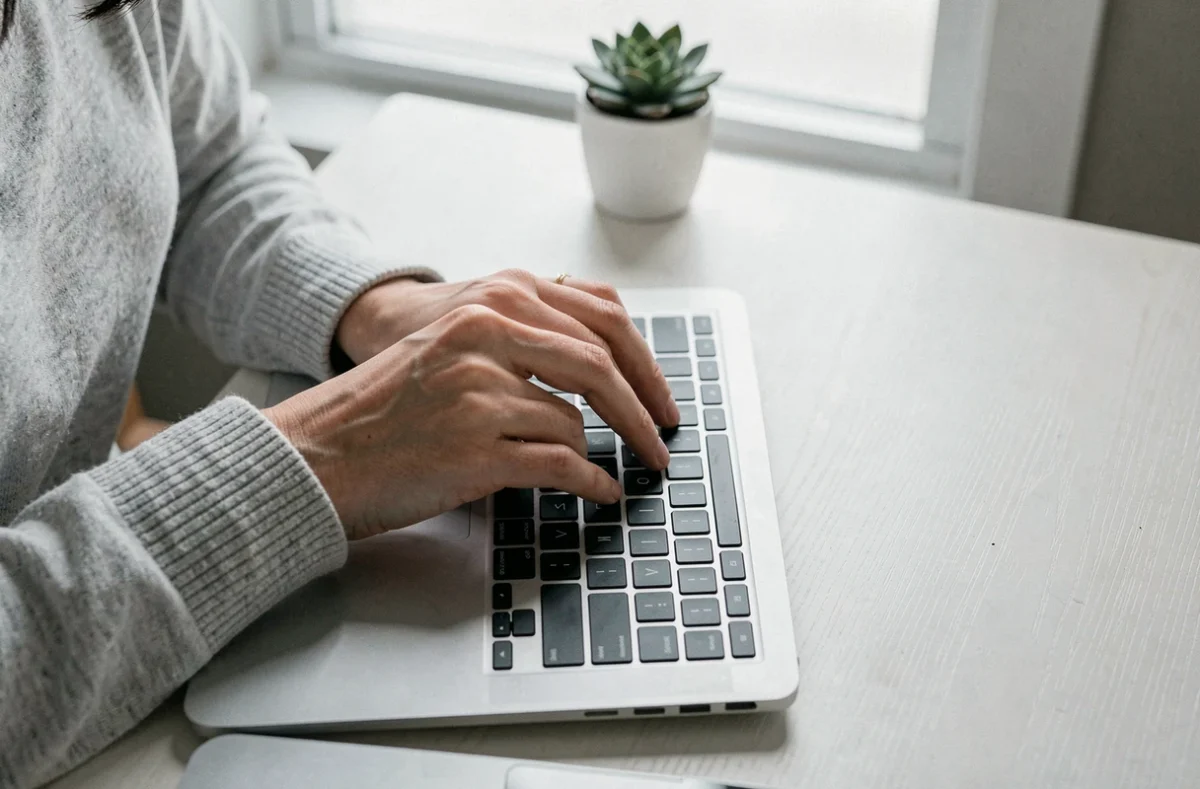 Femme appuyant sur la touche flèche gauche d'un clavier MacBook Pro, vue de dessus en plan serré